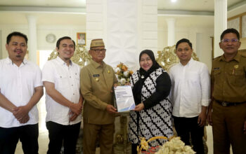 Ketua KPU Bone Bolango, Sutenty Lamuhu didampingi Komisioner lainnya, saat menyerahkan laporan Plakat Pengembalian Dana Hibah oleh KPU Bone Bolango kepada Pemerintah Kabupaten Bone Bolango yang diterima oleh Bupati Ismet Mile, di Bandayo Rumah Dinas Bupati, Senin (5/5/2025). (F.Onal)/Hibata.id