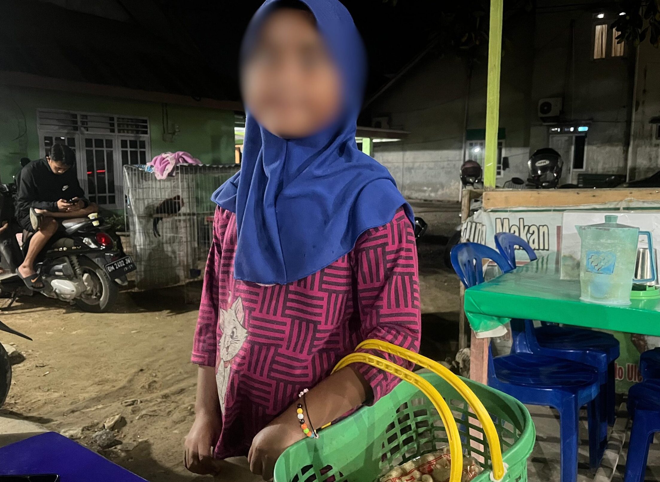 Seorang anak menjajakan keripik di sudut jalan Kota Gorontalo, Senin (16/6/2025) malam. Di saat teman sebayanya pulang sekolah dan beristirahat, ia masih bertaruh tenaga demi membantu ekonomi keluarga. Foto: Hibata.id