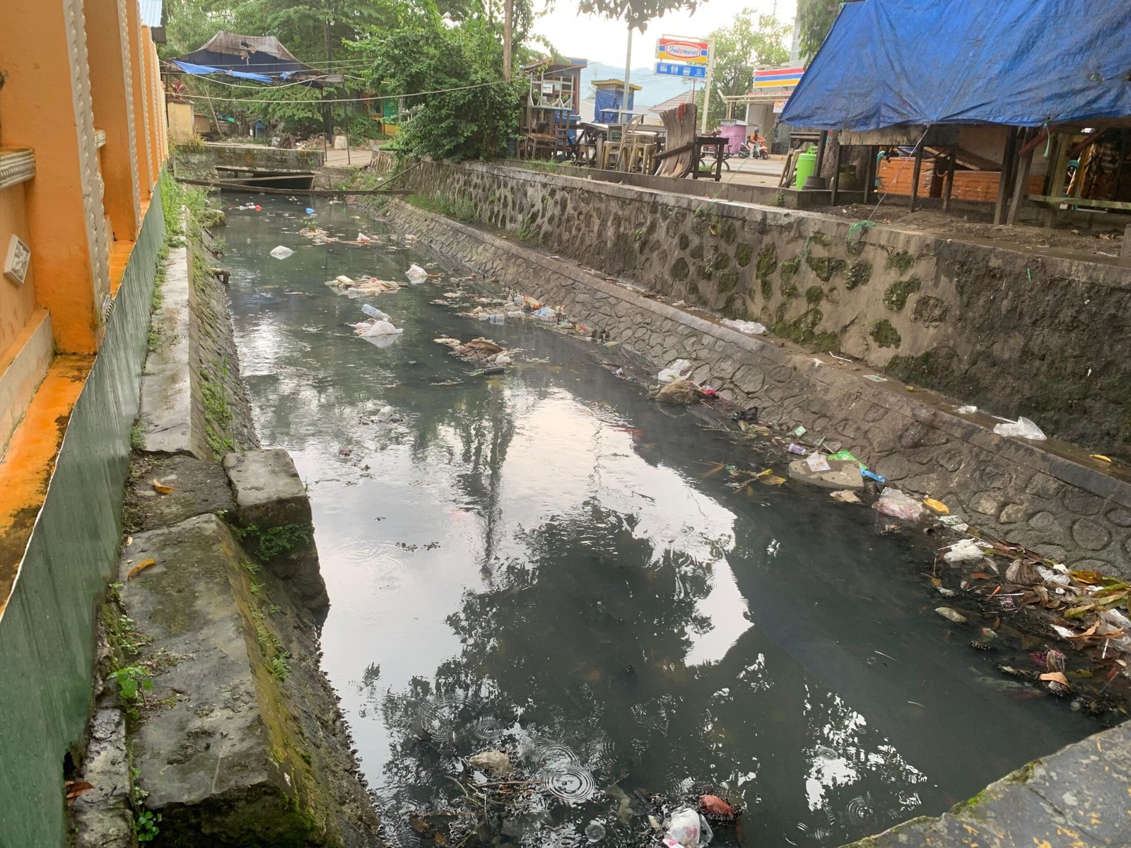 Kondisi saluran air di kawasan wisata kuliner Kalimadu, Kota Gorontalo, tampak dipenuhi sampah sisa makanan dan plastik, Senin (23/6/2025). Limbah ini dikhawatirkan mencemari lingkungan dan mengganggu kenyamanan pengunjung Foto: Hibata.id