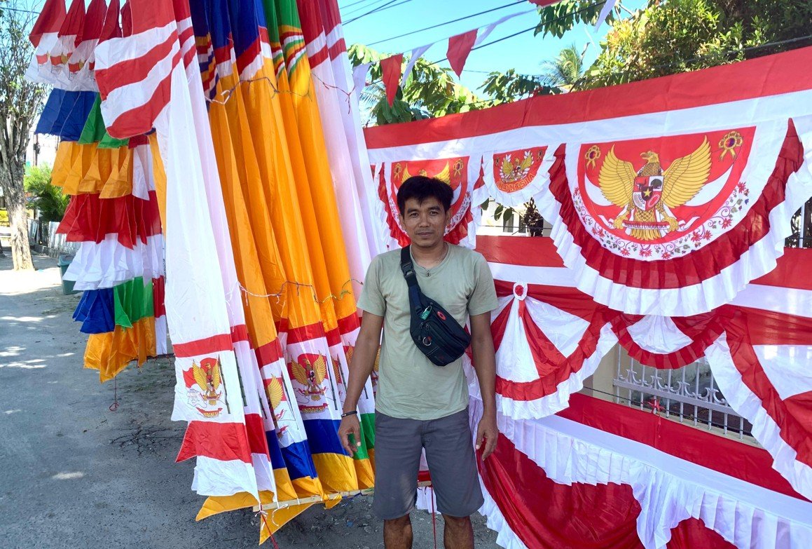 Ansar, pedagang bendera merah putih dan Ornamen kemerdekaan—umbul-umbul, kain dekorasi, hingga miniatur garuda. (Foto: Randa Damaling/Hibata.id)