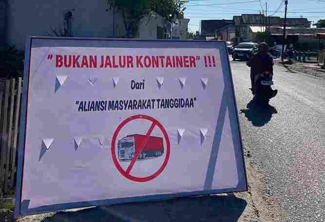 Baliho milik Aliansi Masyarakat Tanggidaa yang secara tegas menolak aktivitas operasional mobil kontainer yang melintasi jalan kota di luar jam operasional resmi. (Foto: Dok. Istw)