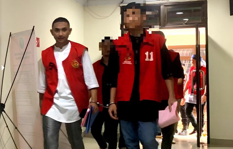 Muhammad Amin Ramadhan, lulusan Institut Pemerintahan Dalam Negeri (IPDN), memasuki ruang sidang utama Pengadilan Negeri Gorontalo dengan mengenakan rompi tahanan dan kedua tangan terborgol saat sidang perdana digelar/Hibata.id