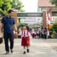 lustrasi seorang ayah sedang menantarkan anaknya di hari pertama sekolah. (Foto: AI Gemini)