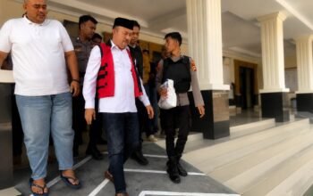 Terdakwa kasus dugaan korupsi Program Hibah Air Minum SR-MBR PUDAM Tirta Gerbang Emas Gorontalo Utara, Muksin Badar, digiring menuju kendaraan usai menjalani sidang pembacaan putusan di Pengadilan Tipikor pada Pengadilan Negeri Gorontalo, Jumat (24/7/2026)/Hibata.id