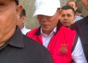 Salah satu tersangka dugaan korupsi dana hibah KONI Gorontalo saat digiring petugas menuju kendaraan tahanan, Jumat (21/8/2026)/Hibata.id