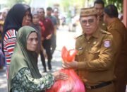 Sekda Bone Bolango Iwan Mustapa menyerahkan bahan pangan di kegiatan Pasar Murah Bersubsidi di Kecamatan Bulango Selatan, Senin (28/9/2026)/Hibata.id
