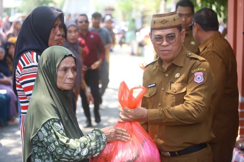 Sekda Bone Bolango Iwan Mustapa menyerahkan bahan pangan di kegiatan Pasar Murah Bersubsidi di Kecamatan Bulango Selatan, Senin (28/9/2026)/Hibata.id