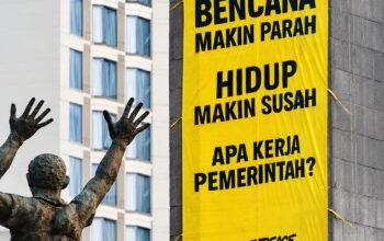 Aktivis Greenpeace Indonesia membentangkan spanduk berisi desakan penanganan krisis iklim di Patung Selamat Datang, Bundaran HI, Jakarta, Selasa (20/10/2026).
