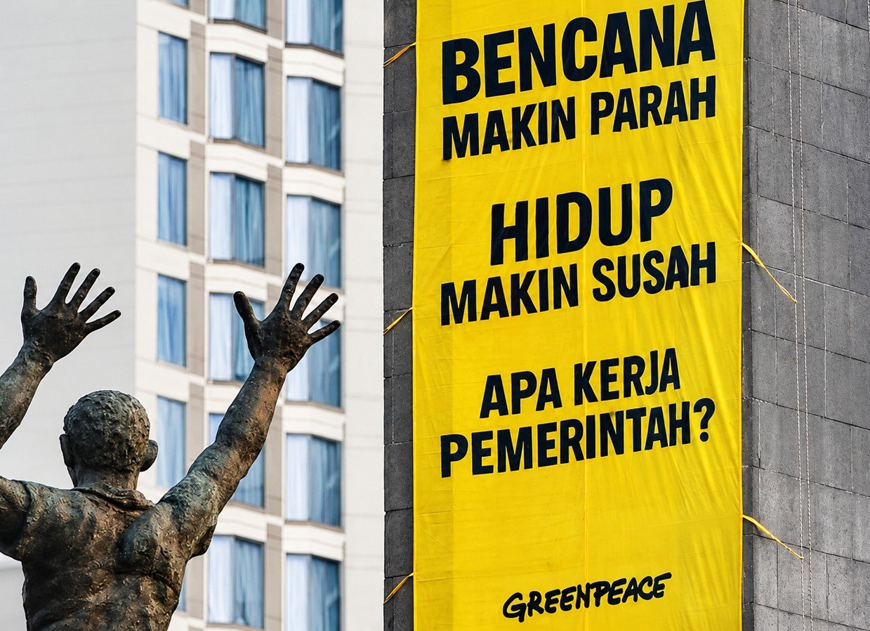 Aktivis Greenpeace Indonesia membentangkan spanduk berisi desakan penanganan krisis iklim di Patung Selamat Datang, Bundaran HI, Jakarta, Selasa (20/10/2026).