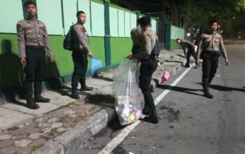 Personel Polresta Balikpapan bersama warga membersihkan sampah di kawasan Tugu Tangan Gunung Pasir setelah kegiatan nobar Indonesia melawan Thailand, Senin dini hari (5/10/2026)/Hibata.id