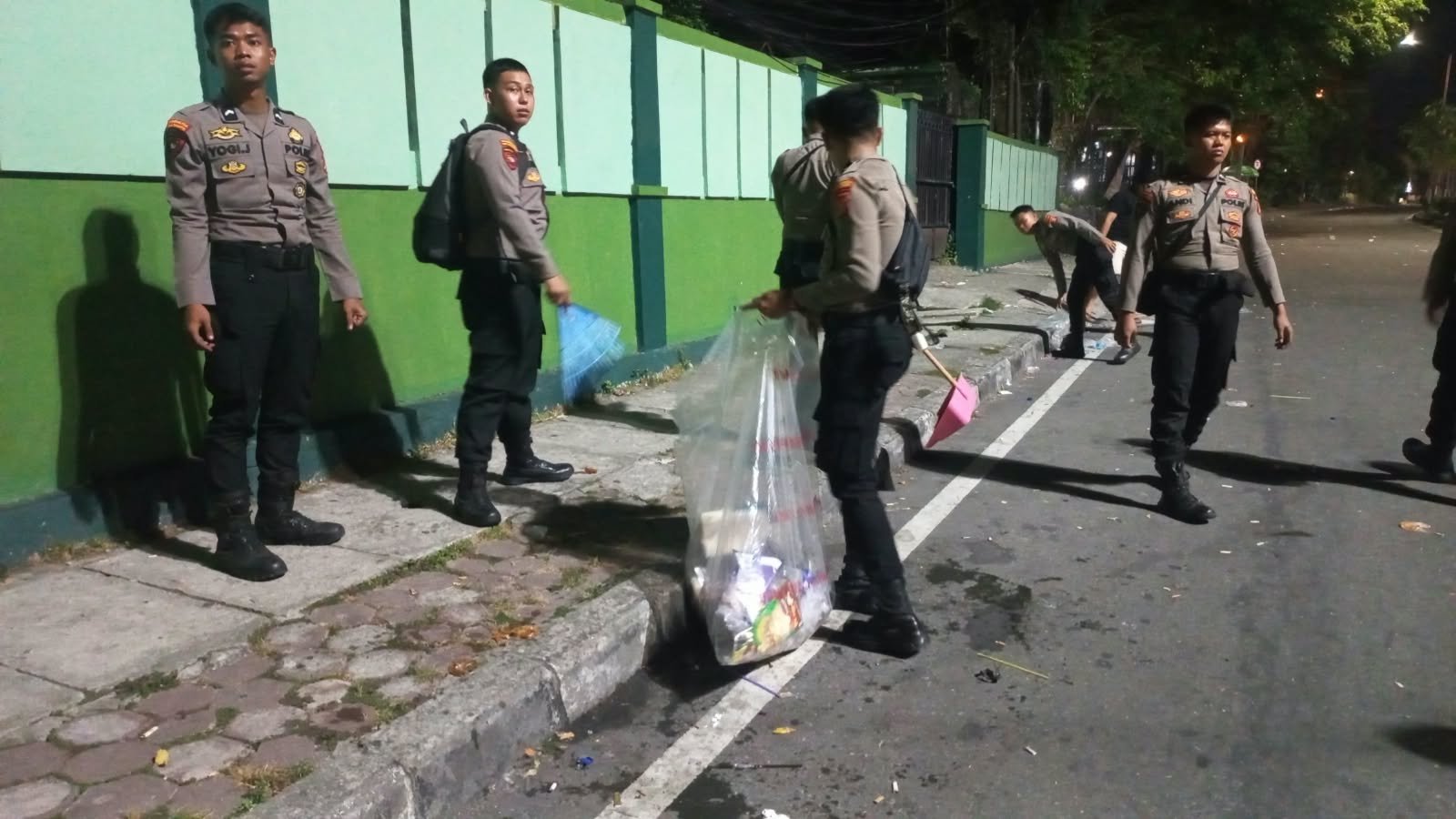 Personel Polresta Balikpapan bersama warga membersihkan sampah di kawasan Tugu Tangan Gunung Pasir setelah kegiatan nobar Indonesia melawan Thailand, Senin dini hari (5/10/2026)/Hibata.id